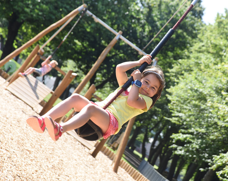 A girl smiling on a zip line. It is a sunny day. 